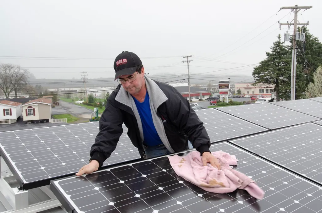 Technician wiping dust off solar panels by hand
